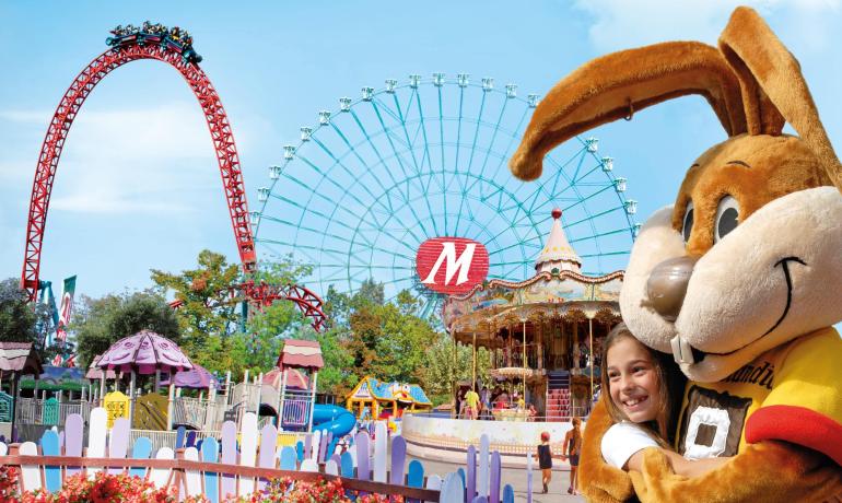 Freizeitpark mit Achterbahn, Riesenrad und Maskottchen, das ein glückliches Kind umarmt.