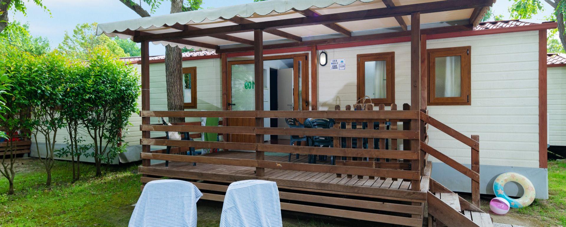 Casa mobile con veranda e sedie a sdraio in giardino.