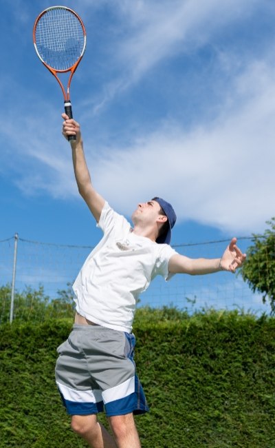 Giocatore di tennis serve all'aperto in una giornata soleggiata.