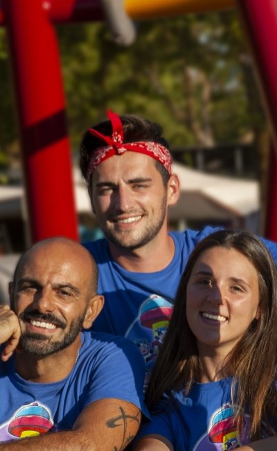 Gruppo di amici sorridenti con magliette blu e sfondo colorato.