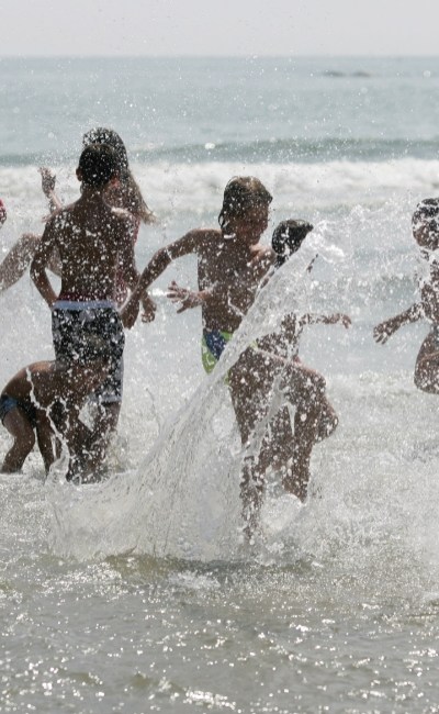 Bambini giocano e spruzzano acqua al mare.