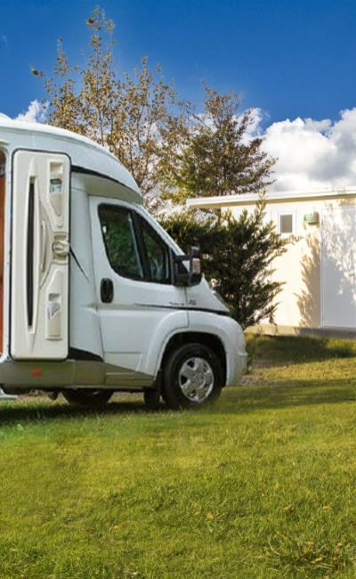 Camper parked near a building in a green area.