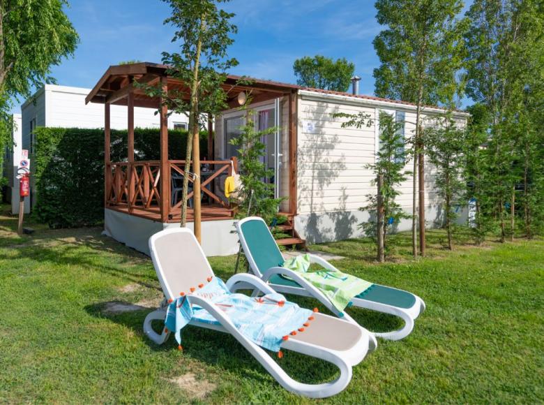 Casetta con veranda e sdraio in giardino verde.