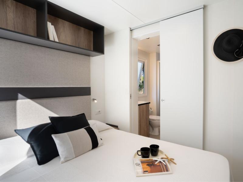 Camera moderna con letto, cuscini e bagno privato.