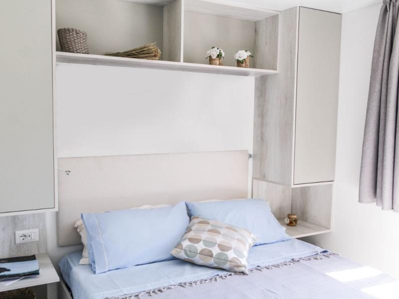 Camera da letto moderna con cuscini blu e decorazioni semplici.