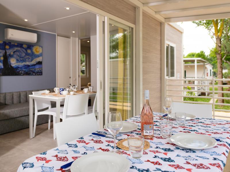 Terrazza accogliente con tavola apparecchiata, vino rosé e vista su giardino verde.