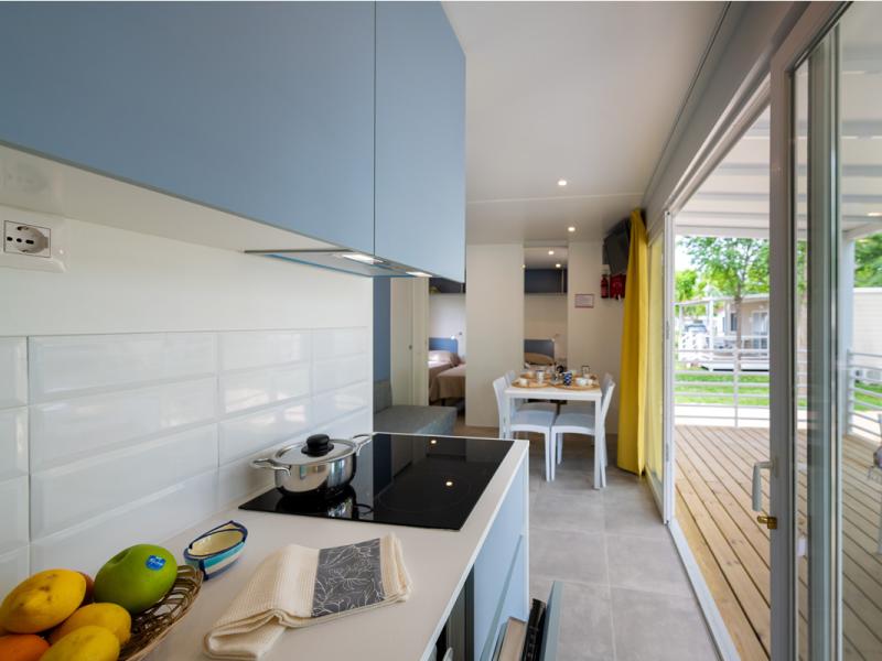 Cucina luminosa, moderna, con vista su terrazza verde e accogliente.