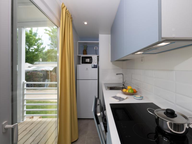 Cucina moderna e luminosa con tende gialle e vista sul giardino.