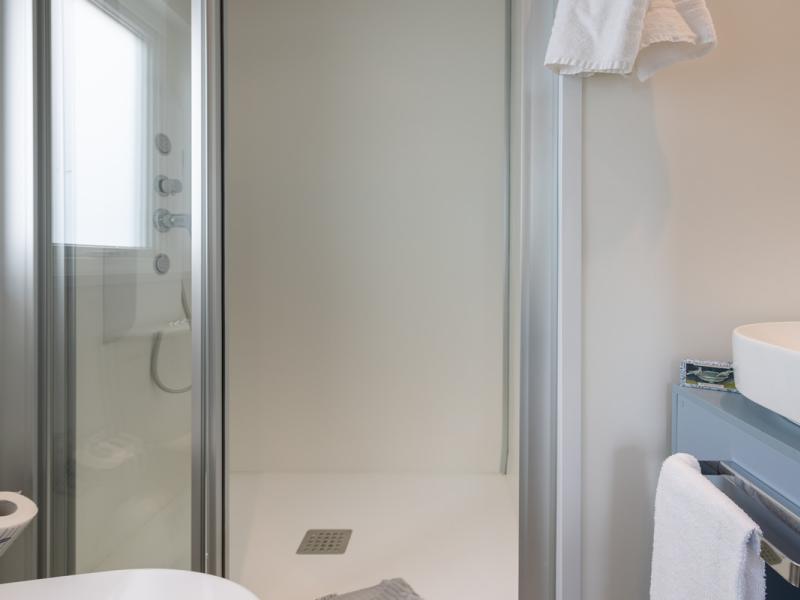 Bagno moderno, minimalista, con doccia elegante e lavabo bianco.