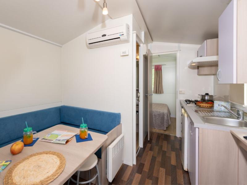 Piccola cucina con tavolo, sedie e camera da letto.