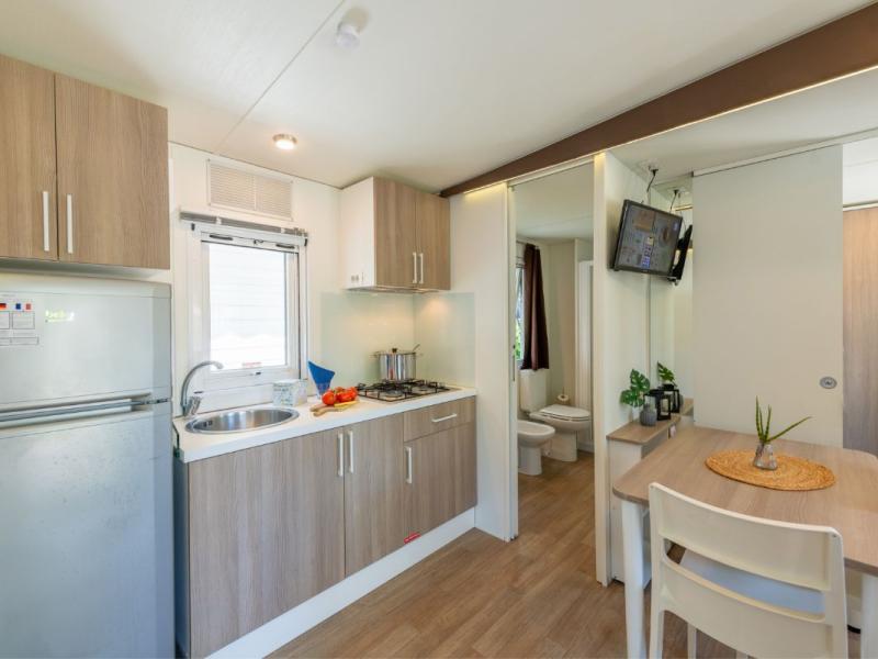 Cucina compatta con tavolo, bagno visibile sul retro.
