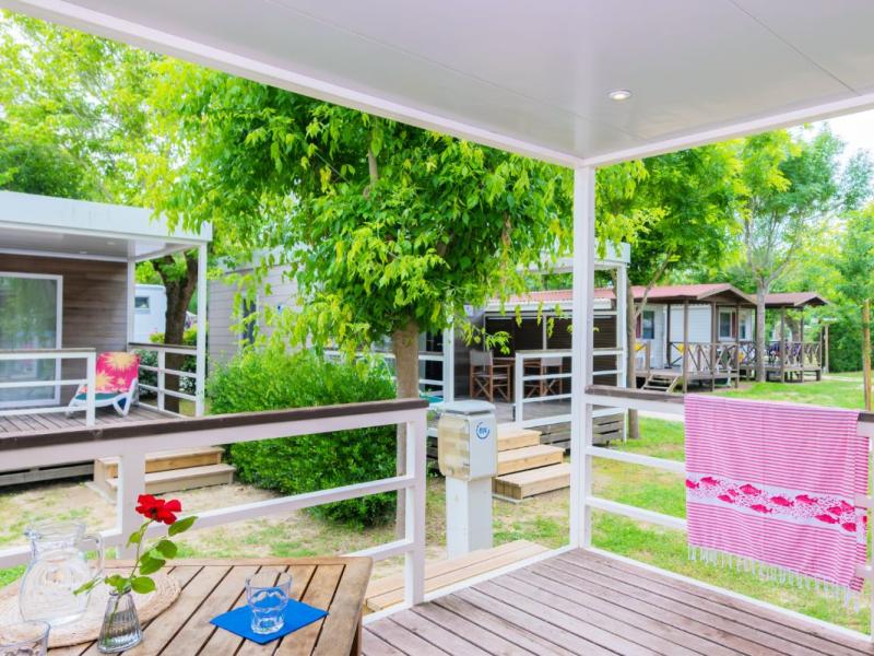 Veranda di legno con vista su bungalow e alberi verdi.