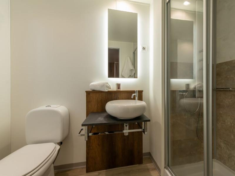 Bagno moderno con doccia, specchio illuminato e lavabo elegante.