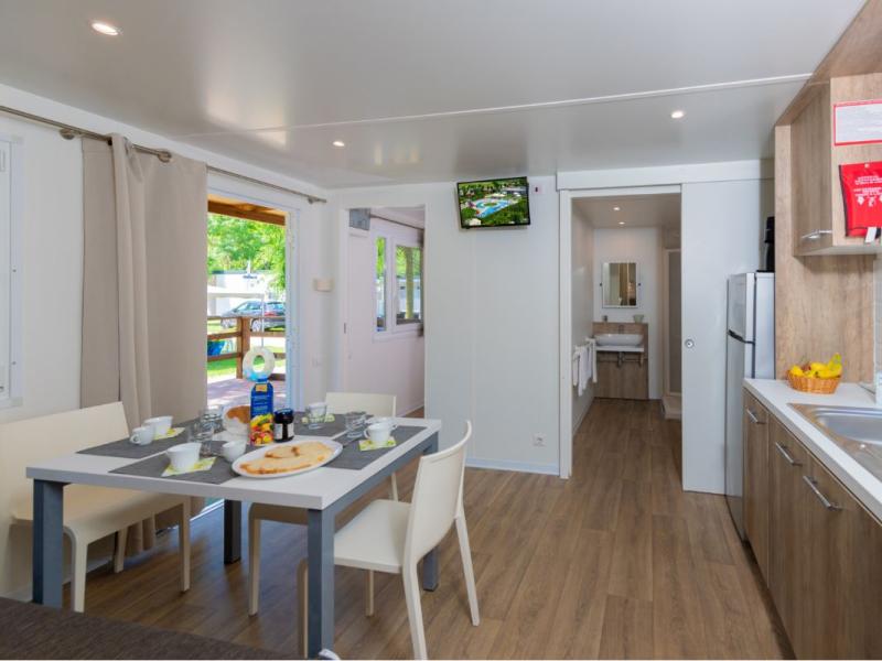 Interno di una cucina moderna con tavolo apparecchiato e vista sul giardino.