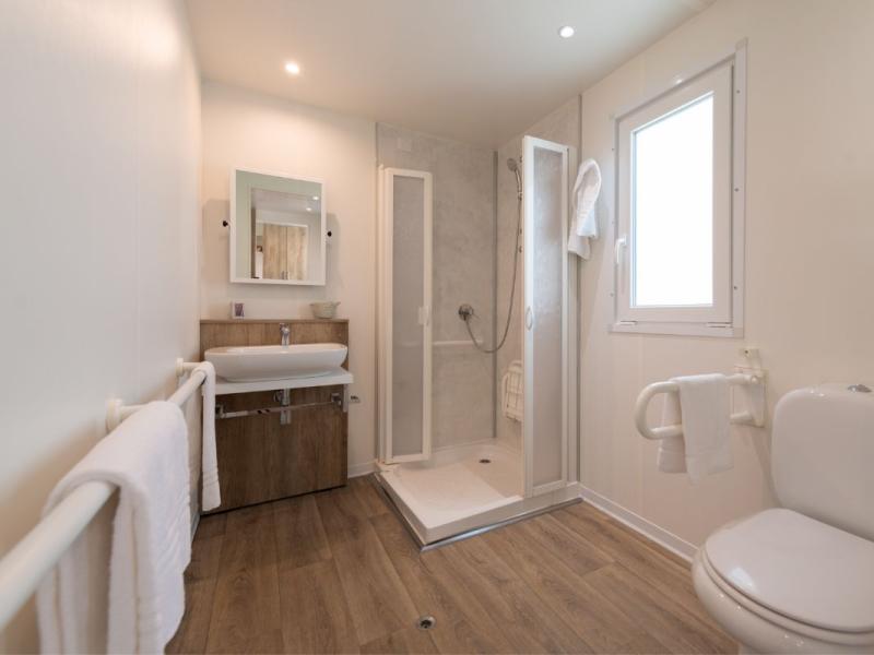 Bagno moderno con doccia, lavabo e WC, pavimento in legno.